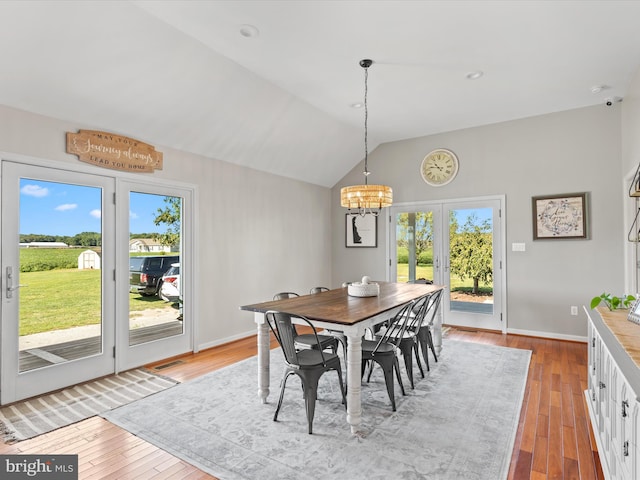 dining space featuring light wood-type flooring, lofted ceiling, and a chandelier