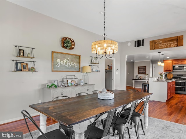 dining room with light wood-type flooring and an inviting chandelier