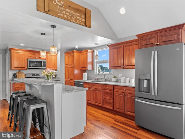 kitchen featuring appliances with stainless steel finishes, a kitchen island, a kitchen bar, and light hardwood / wood-style floors