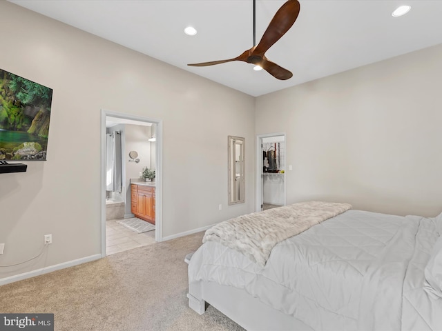 bedroom with light carpet, ensuite bathroom, and ceiling fan