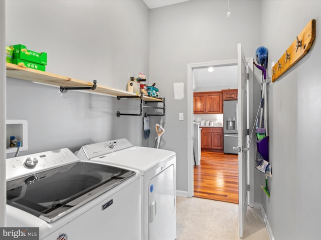 clothes washing area with light wood-type flooring and washer and dryer