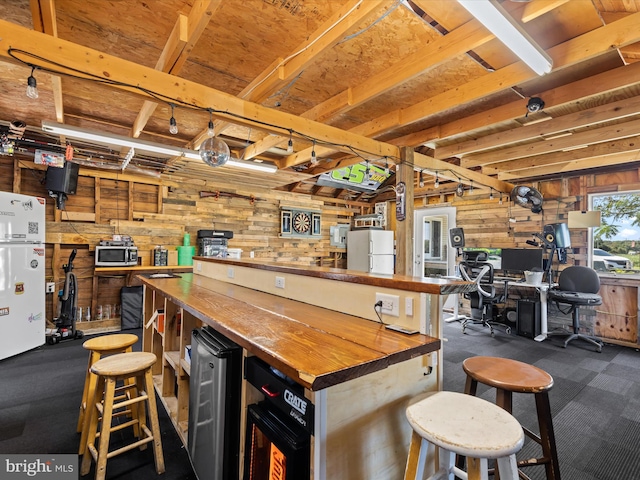 interior space featuring dark carpet, wood walls, white fridge, a kitchen breakfast bar, and butcher block counters