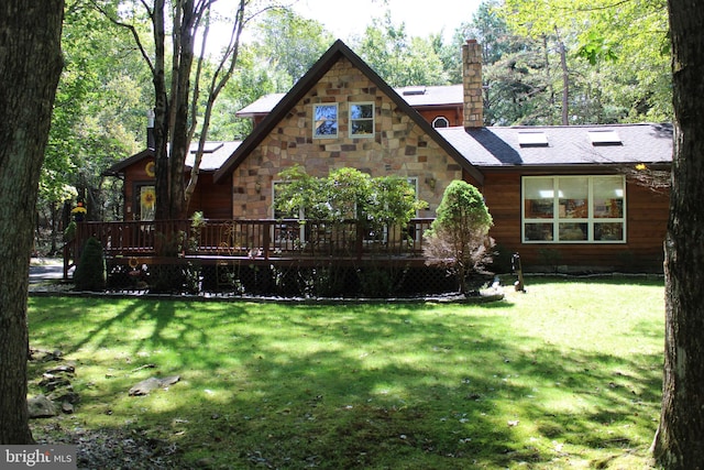 rear view of property featuring a lawn and a deck