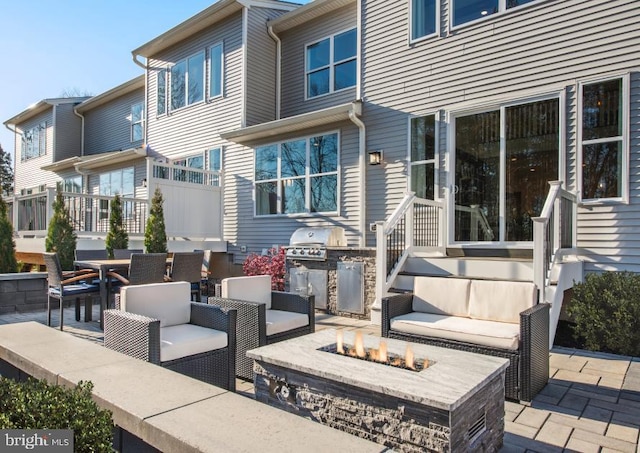 view of patio with exterior kitchen and an outdoor living space with a fire pit