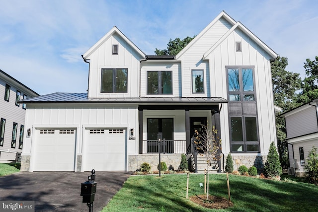 modern farmhouse with a garage, a front lawn, and covered porch