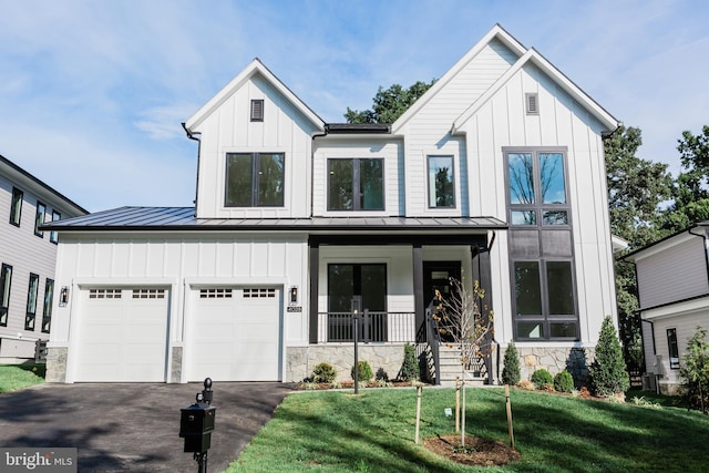 modern farmhouse style home featuring a standing seam roof, aphalt driveway, a porch, board and batten siding, and a garage