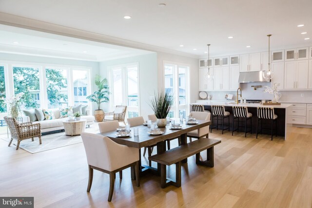 dining area featuring ornamental molding, sink, and light hardwood / wood-style floors