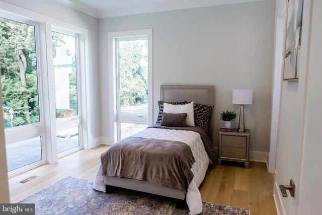 bedroom featuring crown molding, multiple windows, access to exterior, and light hardwood / wood-style floors