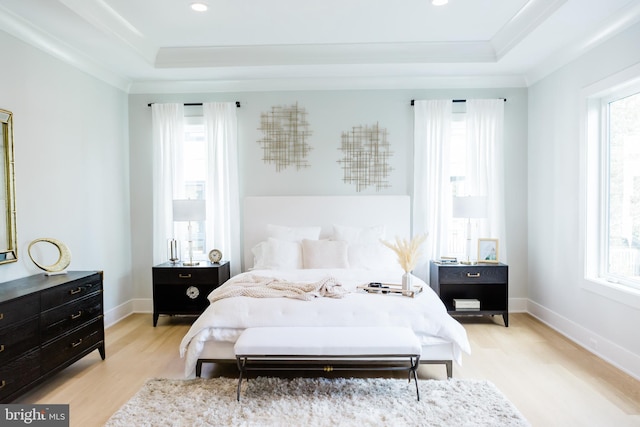 bedroom with a tray ceiling, multiple windows, and light hardwood / wood-style floors