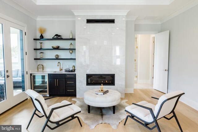 interior space with beverage cooler, french doors, a tile fireplace, and light hardwood / wood-style flooring