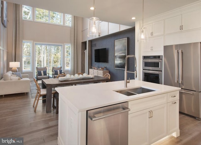 kitchen featuring light wood-type flooring, a sink, open floor plan, white cabinetry, and appliances with stainless steel finishes