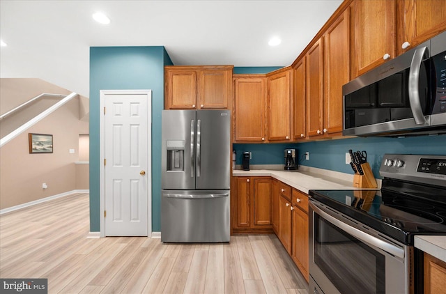 kitchen featuring light countertops, brown cabinets, appliances with stainless steel finishes, and light wood-type flooring