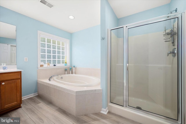 bathroom with visible vents, a garden tub, a stall shower, wood finished floors, and vanity