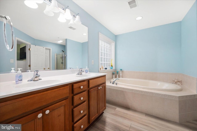 full bathroom featuring a shower stall, a garden tub, visible vents, and a sink