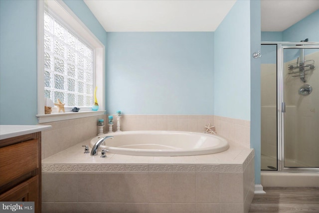 bathroom with wood finished floors, vanity, a bath, and a shower stall