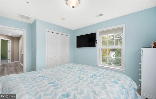 bedroom featuring visible vents, a closet, and wood finished floors