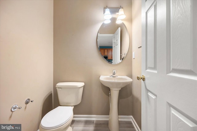 bathroom featuring toilet, wood finished floors, and baseboards