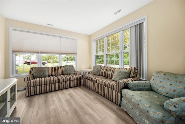 living area with light wood-type flooring, visible vents, and a healthy amount of sunlight