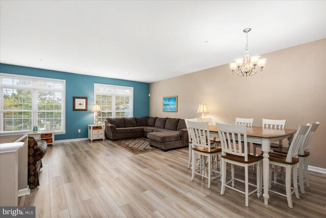 dining area with light wood-style flooring, baseboards, and an inviting chandelier