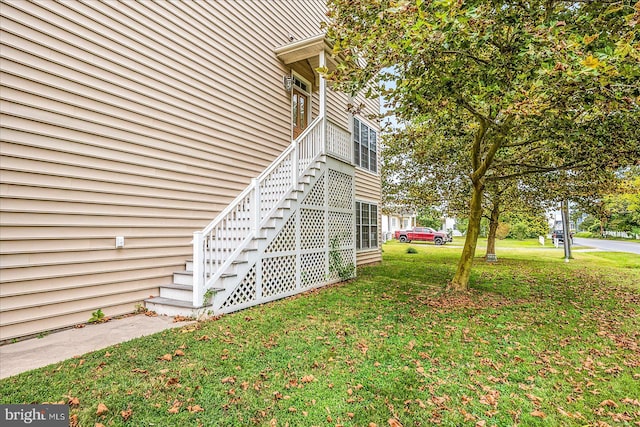 view of home's exterior featuring a lawn and stairs