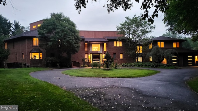 view of front of home with a front yard, brick siding, and driveway