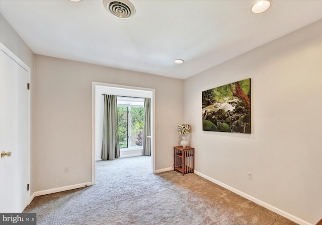 carpeted empty room with visible vents and baseboards