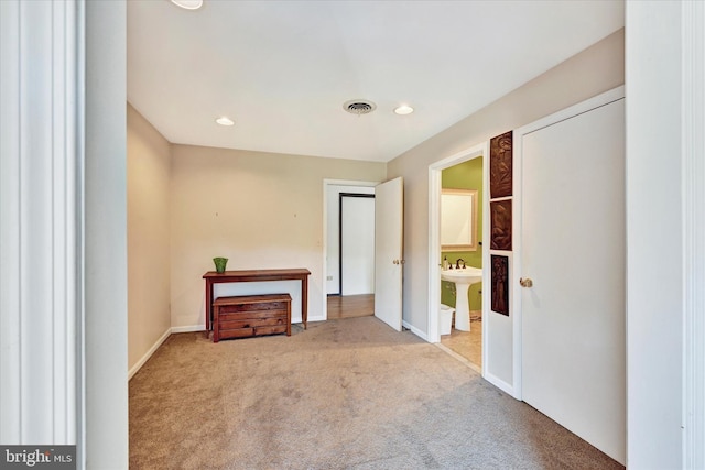 empty room with carpet, visible vents, baseboards, recessed lighting, and a sink