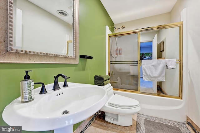 full bathroom featuring a sink, visible vents, toilet, and shower / bath combination with glass door