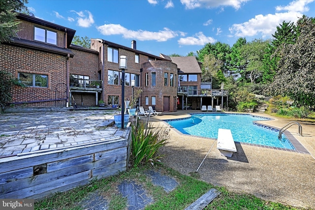 pool featuring a deck, a patio, and a diving board