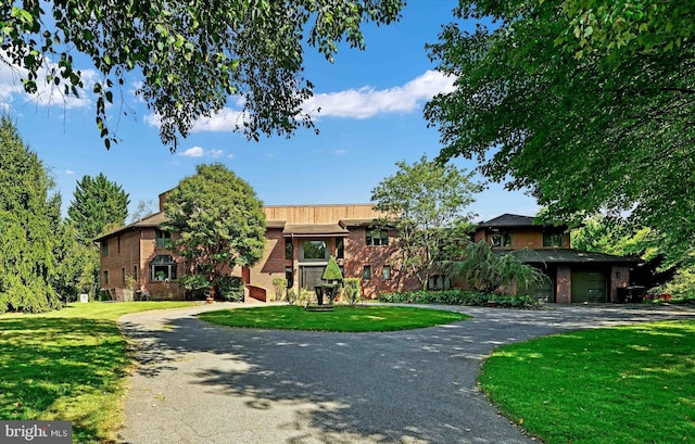 view of front facade with aphalt driveway, brick siding, and a front lawn