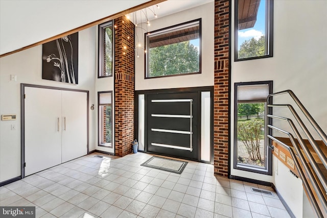 tiled entryway with a high ceiling, baseboards, and visible vents