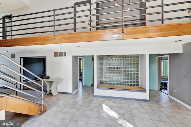 interior space featuring visible vents, baseboards, and a towering ceiling