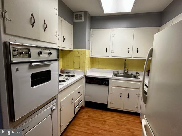 kitchen featuring white cabinetry, sink, and white appliances