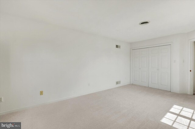 unfurnished bedroom featuring a closet and light carpet