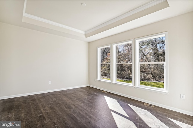 unfurnished room featuring crown molding, a tray ceiling, and dark hardwood / wood-style floors