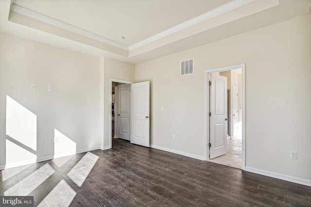 unfurnished bedroom with a raised ceiling, dark hardwood / wood-style floors, and crown molding