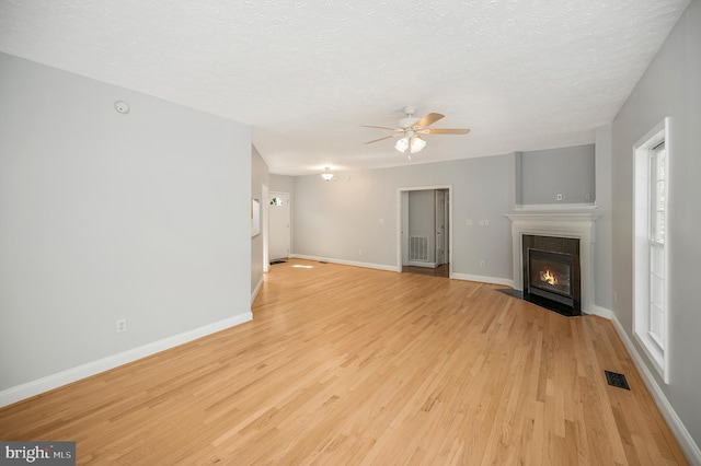 unfurnished living room featuring a textured ceiling, light wood-type flooring, and ceiling fan