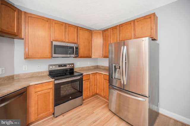 kitchen featuring appliances with stainless steel finishes and light hardwood / wood-style flooring