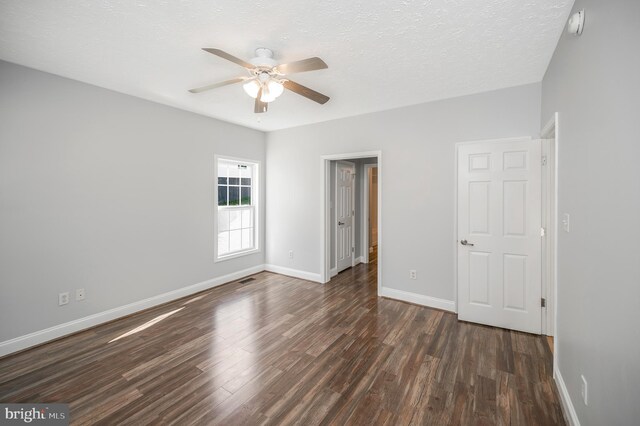 unfurnished bedroom with dark hardwood / wood-style flooring, a textured ceiling, and ceiling fan