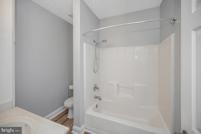 full bathroom featuring vanity, shower / bathing tub combination, hardwood / wood-style flooring, toilet, and a textured ceiling