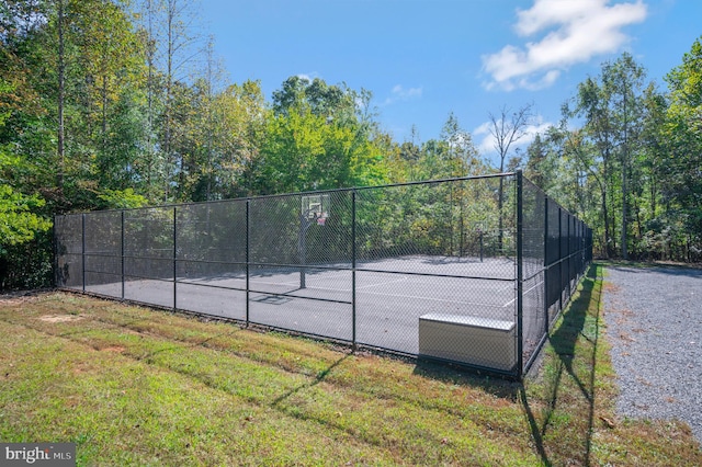 view of sport court with basketball hoop and a lawn