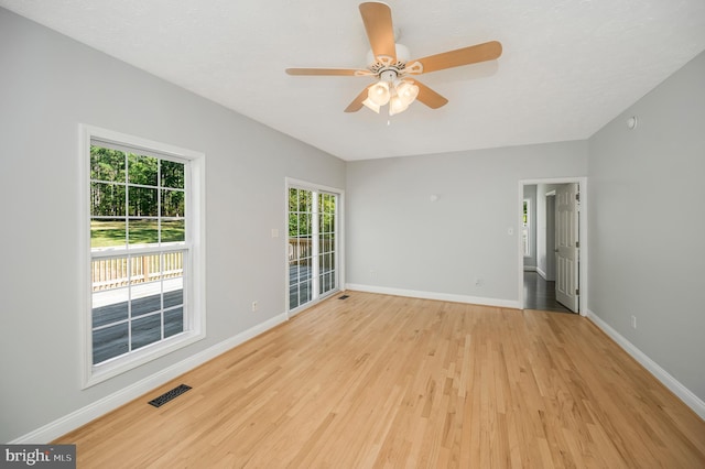 spare room featuring ceiling fan, light wood-type flooring, and a wealth of natural light