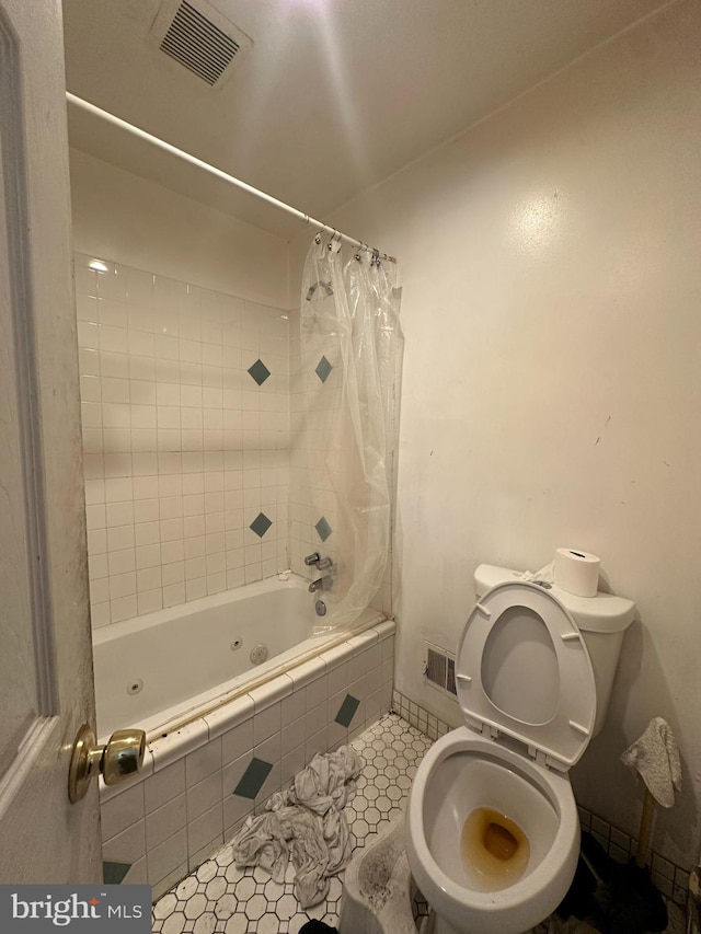 bathroom featuring shower / bath combo with shower curtain, toilet, and tile patterned floors