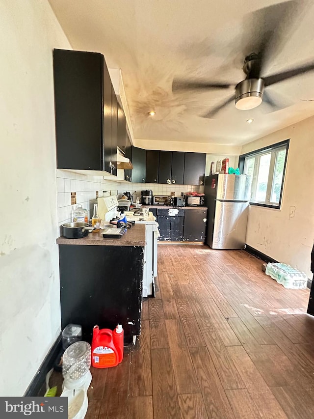 kitchen with backsplash, appliances with stainless steel finishes, and hardwood / wood-style flooring