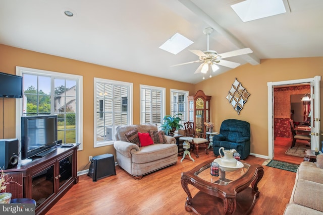 living room featuring ceiling fan, light wood-type flooring, and lofted ceiling with skylight