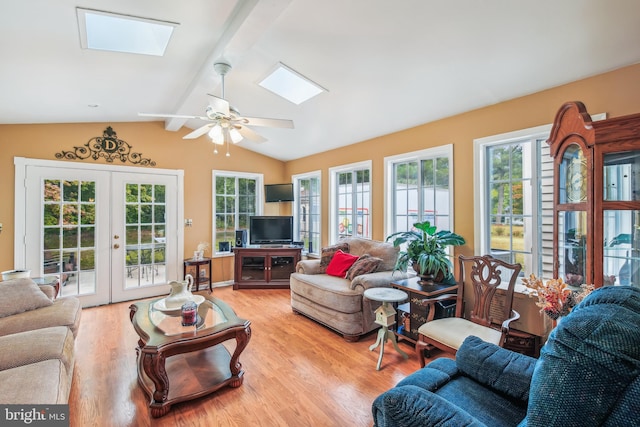 living room featuring light wood-type flooring, lofted ceiling with skylight, ceiling fan, and french doors