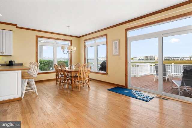 dining space with light hardwood / wood-style floors, crown molding, and an inviting chandelier