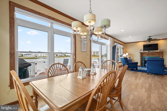 dining space featuring ornamental molding, light wood-type flooring, and a healthy amount of sunlight