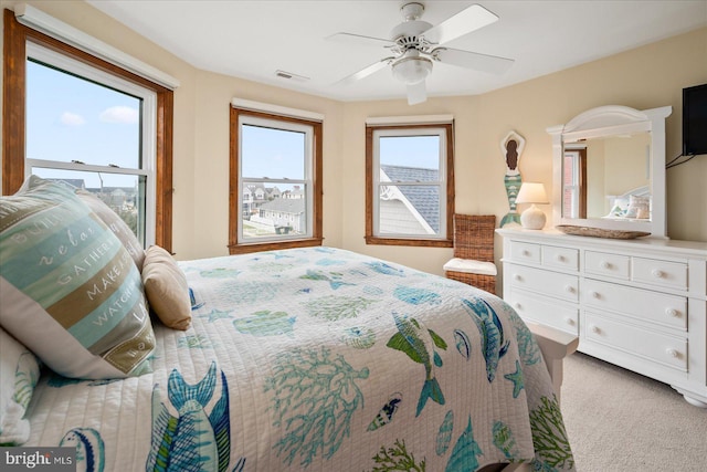 bedroom with light carpet, multiple windows, and ceiling fan