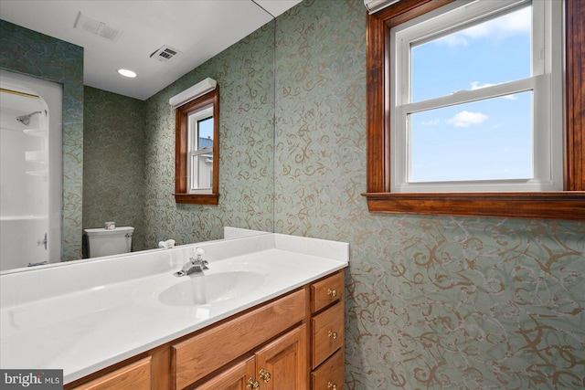 bathroom with toilet, a healthy amount of sunlight, and vanity